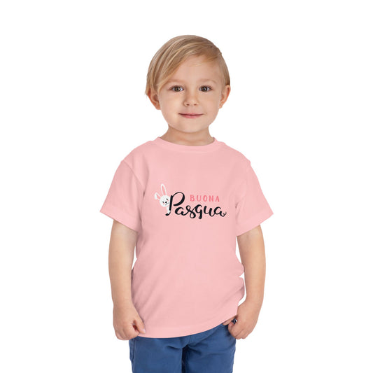 A toddler wearing a pink short sleeve t-shirt with 'Buona Pasqua' text graphic.