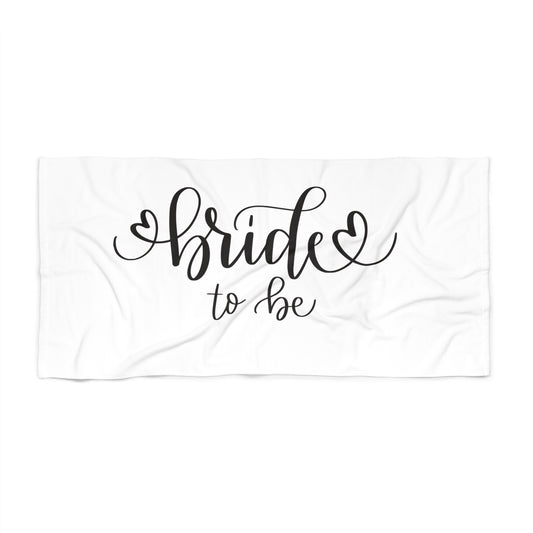 A white beach towel with the phrase 'Bride to be' printed in black cursive text, laying flat.
