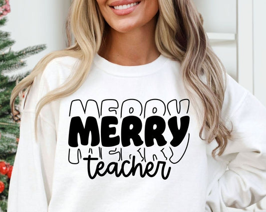 A smiling teacher wearing a white crewneck merry teacher sweatshirt with black text and decorations.