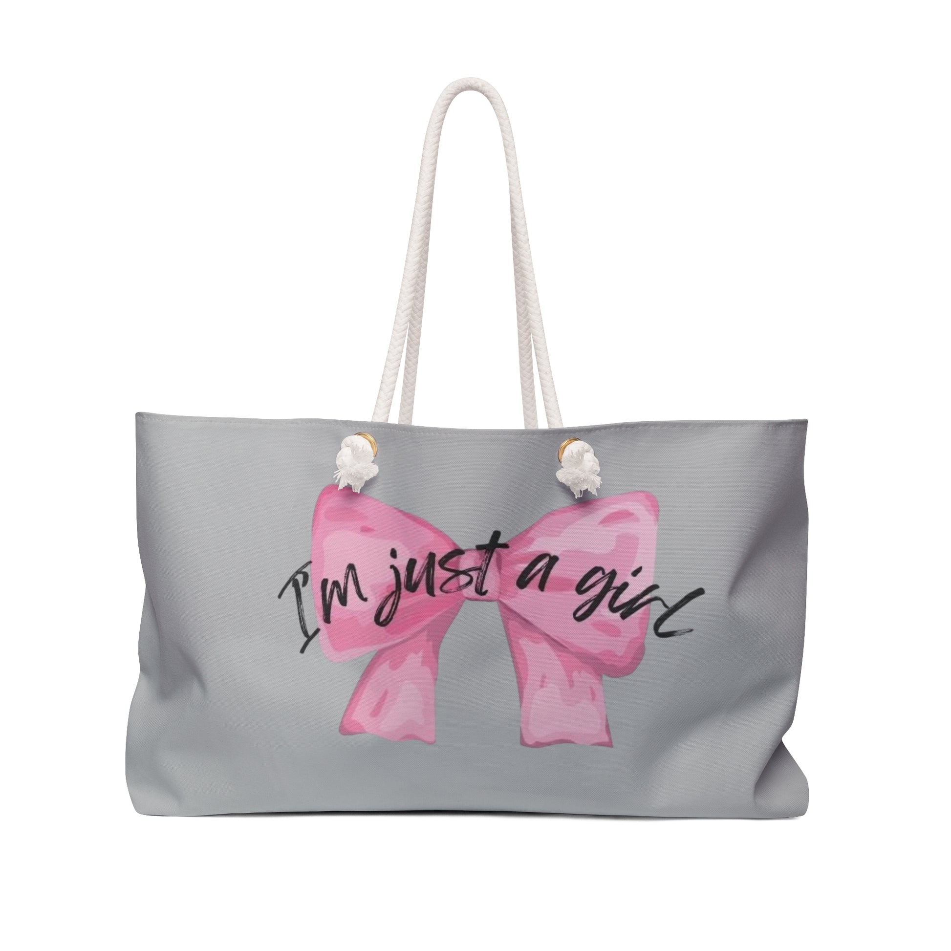 A large tote-style weekender bag with a gray background featuring a floral print. The bag has the text 'I'm just a girl' accompanied by a pink bow graphic on the front.
