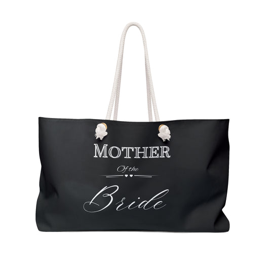 A black tote bag with white text 'MOTHER OF THE BRIDE' printed on the side, featuring two handles.