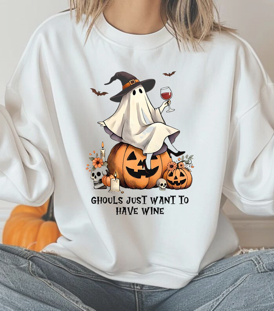 A person wearing a white crewneck sweatshirt with a graphic of a ghost, a pumpkin, and a glass of wine, along with the text 'Ghosts just want to have wine'.
