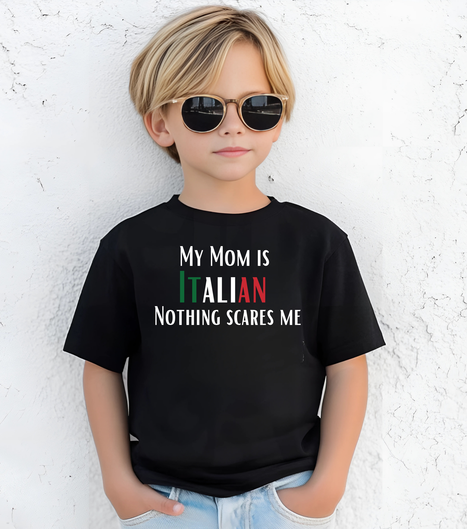 Child wearing a black t-shirt with text standing against a white textured wall