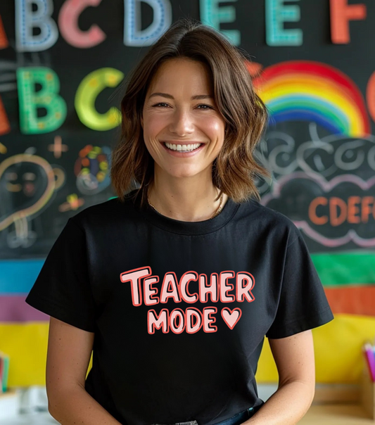 Person wearing a black t-shirt with 'Teacher Mode' text in front of a colorful classroom background.